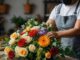 Mejores floristerías en CDMX - Florista arma un ramo de flores de varios colores sobre una mesa de madera