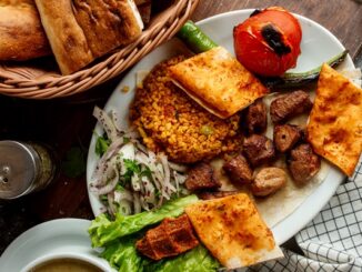 Restaurantes turcos en CDMX - Plato blanco servido con comida tradicional turca y una cesta de pan sobre una mesa de madera