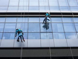 Las 10 mejores empresas de limpieza de vidrios y ventanas en CDMX - Trabajadores de una compañía se cuelgan en cuerdas para limpiar la fachada de un edificio de cristal