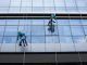 Las 10 mejores empresas de limpieza de vidrios y ventanas en CDMX - Trabajadores de una compañía se cuelgan en cuerdas para limpiar la fachada de un edificio de cristal