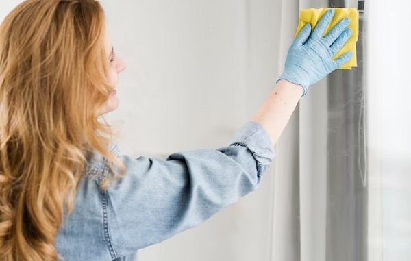 Los 10 mejores servicios de lavado de cortinas en CDMX Mujer remueve el polvo y la suciedad de las ventana y cortinas de una habitación
