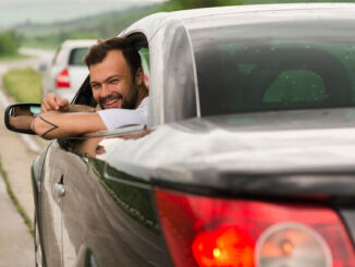 Joven sonríe mientras conduce su nuevo coche deportivo