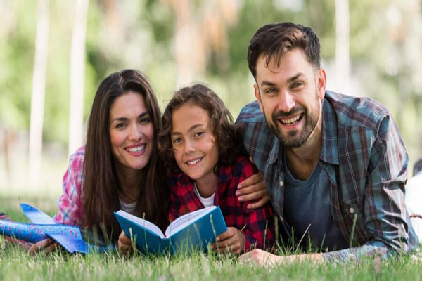 Actividades para año nuevo - Familia feliz sale de paseo al parque y acompaña a su hijo a leer un libro al aire libre