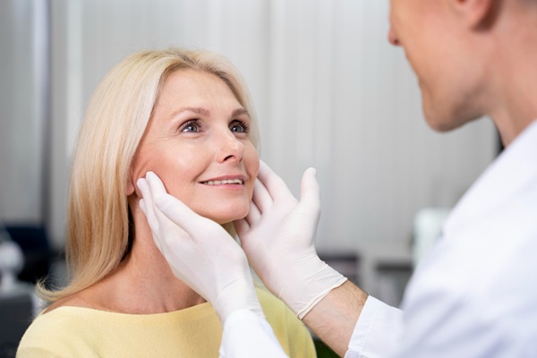 Lifting facial - Esteticista usando sus manos para estirar la piel del rostro de una mujer y evaluar un tratamiento estético