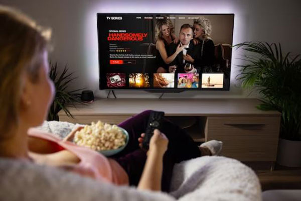 Actividades para año nuevo - Joven disfruta de un maratón de series y películas en casa junto a una taza de palomitas