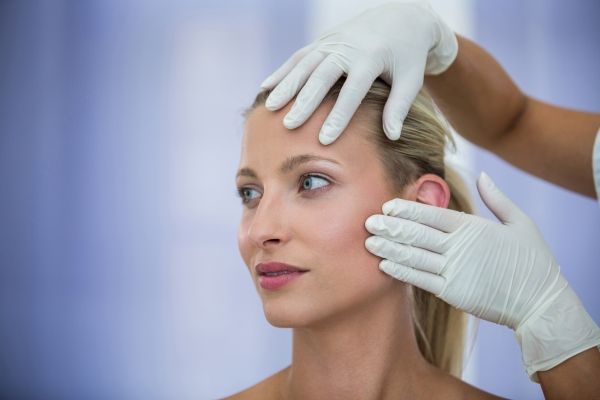 Dermatólogos en CDMX - Dermatólogo examina el rostro de una paciente antes aplicar microinyecciones con ácido hilurónico 