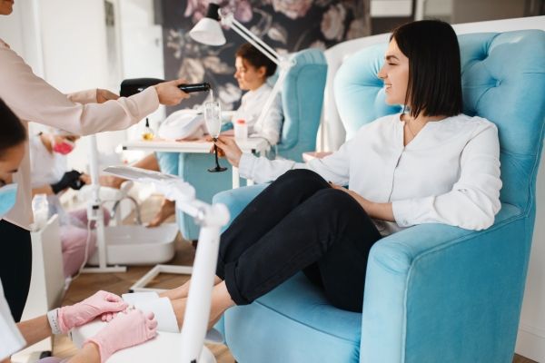 Mejores salones de uñas de CDMX - Mujer recibe una copa de champán mientras le hacen la pedicura