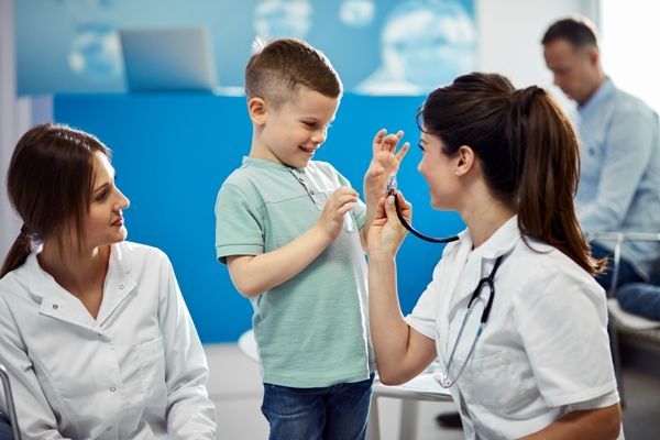 Mejores pediatras CDMX - Doctora juega con un niño mientras lo examina con un estetoscopio