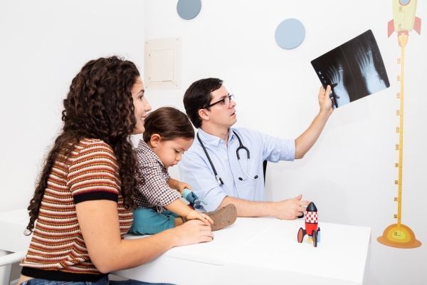Doctor analiza las radiografías de los pies de un niño en su consultorio
