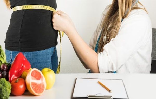 Clínicas de obesidad - Endocrinóloga mide la cintura de una paciente con problemas de sobrepeso