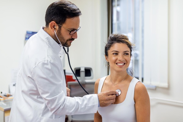 Cardiologistas - Cardiólogo usando un estetoscopio para evaluar el corazón de una mujer y detectar problemas cardiacos