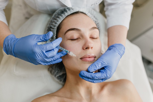 Clínicas dermatológicas en CDMX - Dermatólogo realizando un tratamiento de aumento de labios a una mujer aplicando una inyección de ácido hialurónico
