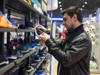 Tiendas de calzado deportivo - Hombre joven observando diversos modelos de zapatos deportivos para escoger el mejor tenis