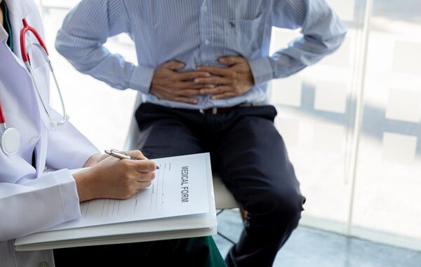 Gastroenterólogos de CDMX - Hombre colocando sus manos en el estómago durante una consulta médica con el gastroenterólogo por problemas digestivos
