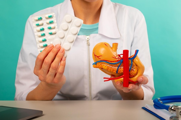 Gastroenterólogos de CDMX - Médico gastroenterólogo sosteniendo en sus manos una maqueta del sistema digestivo y pastillas para tratar el dolor de estómago
