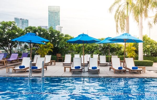 Hoteles con alberca en CDMX - Alberca al aire libre con sombrillas azules y tumbonas en el mejor hotel de CDMX
