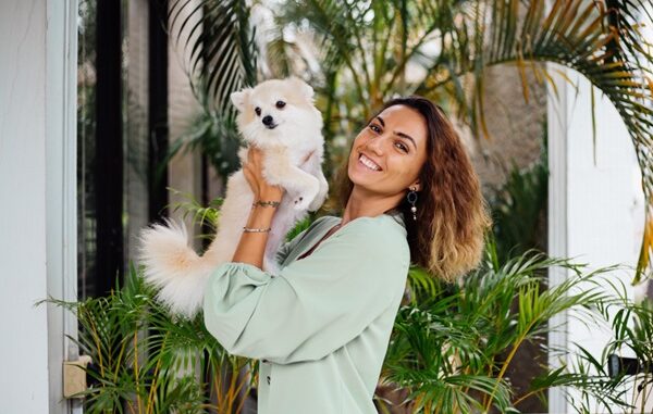Hoteles pet friendly CDMX - Mujer joven feliz sosteniendo en sus manos un perro en la entrada de un hotel pet friendly