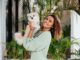 Hoteles pet friendly CDMX - Mujer joven feliz sosteniendo en sus manos un perro en la entrada de un hotel pet friendly