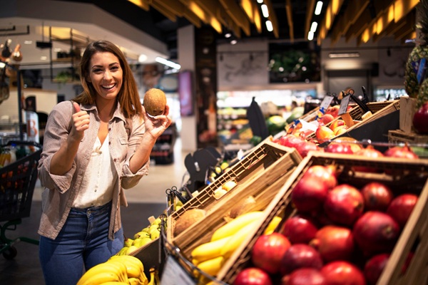 Supermercados en CDMX - Mujer sosteniendo un coco en la mano mientras hace compras en la sección de frutas de un supermercado en CDMX
