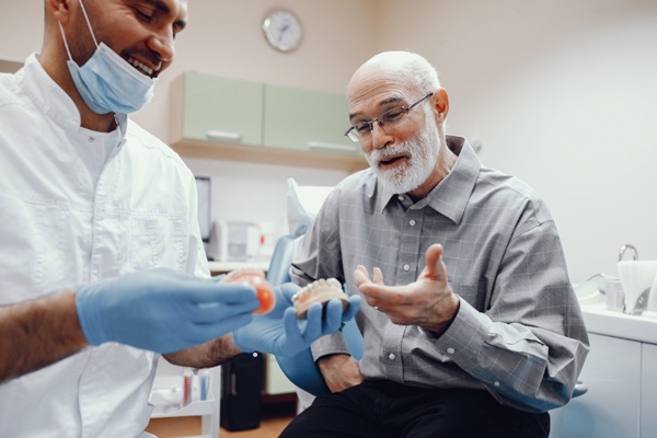Prótesis dental - Odontólogo mostrando a un paciente diversos tipos de prótesis dentales para recuperar la función bucal