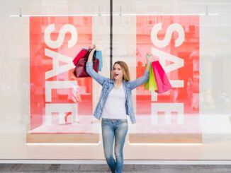 Tiendas outlet - Mujer feliz sosteniendo varias bolsas de compras frente a una tienda outlet en CDMX