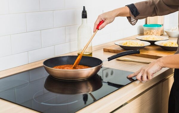 Vitrocerámica - Persona cocinando un guiso en un sartén sobre una placa de vitroceramica en una cocina moderna comprada en CDMX