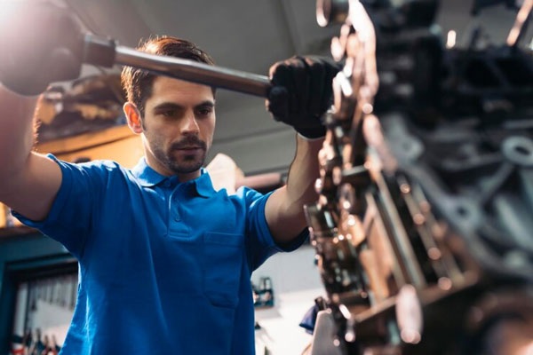 Carreras mejor pagadas - Ingeniero mecánico trabaja en la reparación del motor de un vehículo