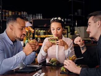 Restaurantes de hamburguesas - Grupo de amigos conversan mientras degustan una hamburguesa en los mejores restaurantes de hamburguesas de CDMX