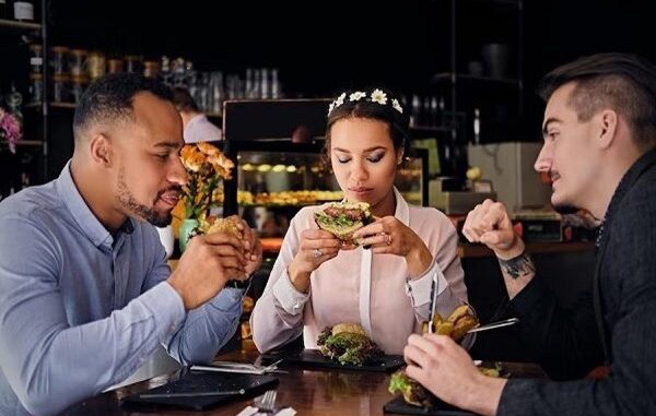 Restaurantes de hamburguesas - Grupo de amigos conversan mientras degustan una hamburguesa en los mejores restaurantes de hamburguesas de CDMX