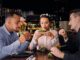 Restaurantes de hamburguesas - Grupo de amigos conversan mientras degustan una hamburguesa en los mejores restaurantes de hamburguesas de CDMX