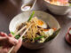 Plano detalle de un ramen asiático con atún, verduras, huevo y fideos