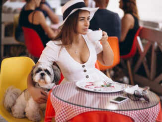 Joven toma un postre y una taza de café en compañía de su perro