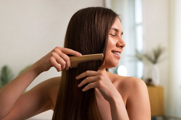 Productos para el pelo - Joven utiliza un peine de madera para llevar a cabo su rutina de cuidado capilar