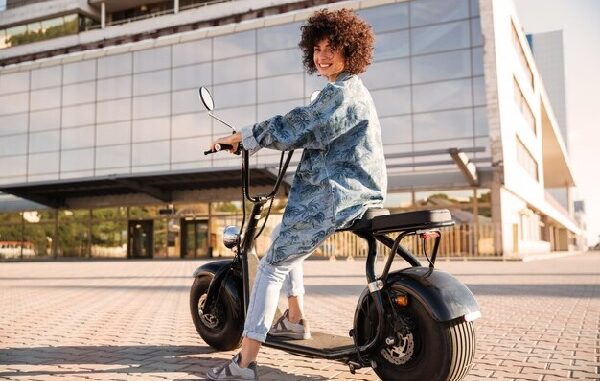 Motos eléctricas CDMX - Mujer de cabello rizado posando sonriente montada en su moto eléctrica en CDMX