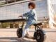 Motos eléctricas CDMX - Mujer de cabello rizado posando sonriente montada en su moto eléctrica en CDMX