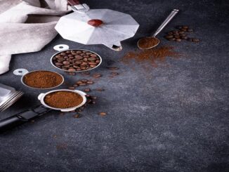 Las mejores marcas de café de CDMX - Utensilios y materiales de café sobre una superficie oscura: cafetera moka, recipientes con granos y café molido, cuchara y algunos granos dispersos.
