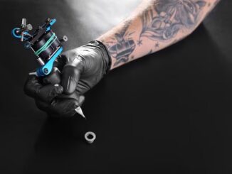 Los mejores tatuadores en CDMX - Mano de un tatuador sosteniendo una máquina de tatuar, la cual va a sumergir en tinta para empezar el tatuaje en CDMX