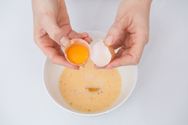 Persona abriendo un huevo para preparar una mascarilla capilar que ayuda a nutrir e hidratar el pelo