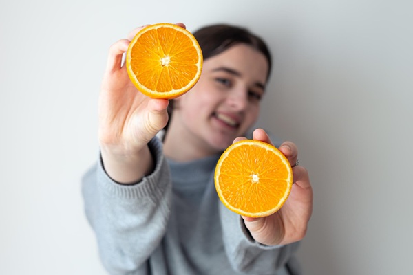 Mujer sosteniendo naranjas en la mano que ayudan a incrementar la vitamina C y aliviar los síntomas de gripe