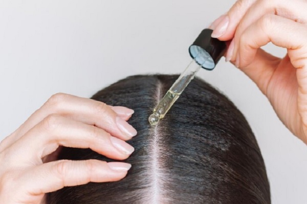 Dejar de ser calvo- persona colocandose minoxidil en el cuero cabelludo
